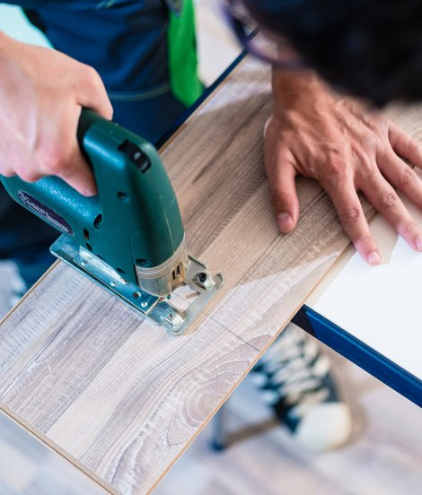 Picture of a man using a tool to cut through a board.