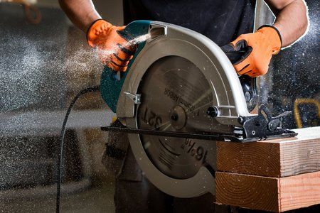 Picture of a man using an electric saw to cut through boards. 