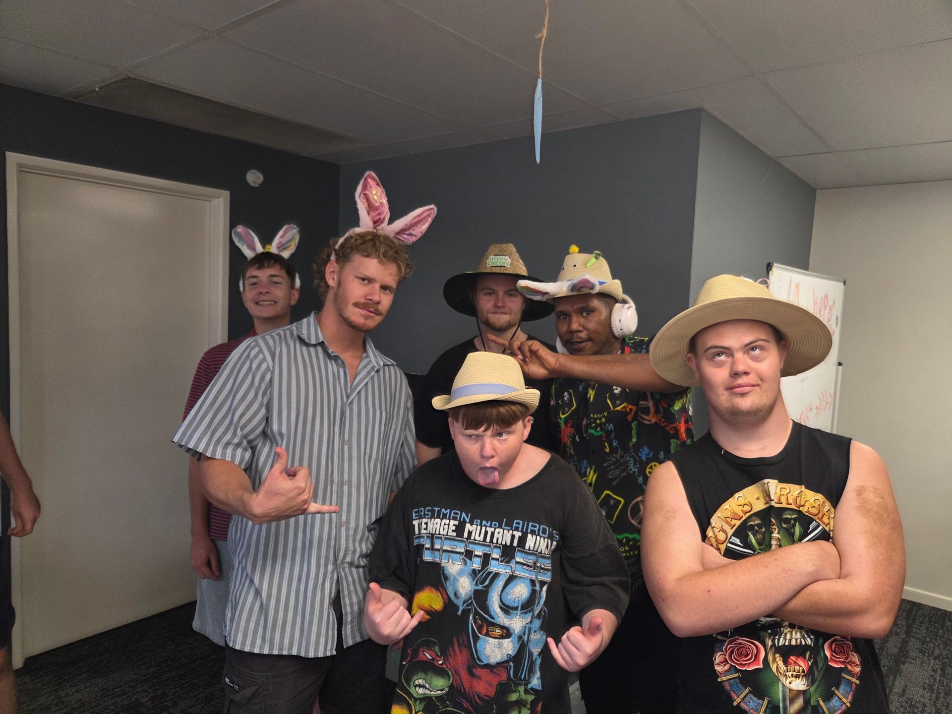 Six people in an indoor room wear festive hats, including bunny ears and straw hats, posing for a group photo — Advanced Therapy Mackay In Mackay, QLD 