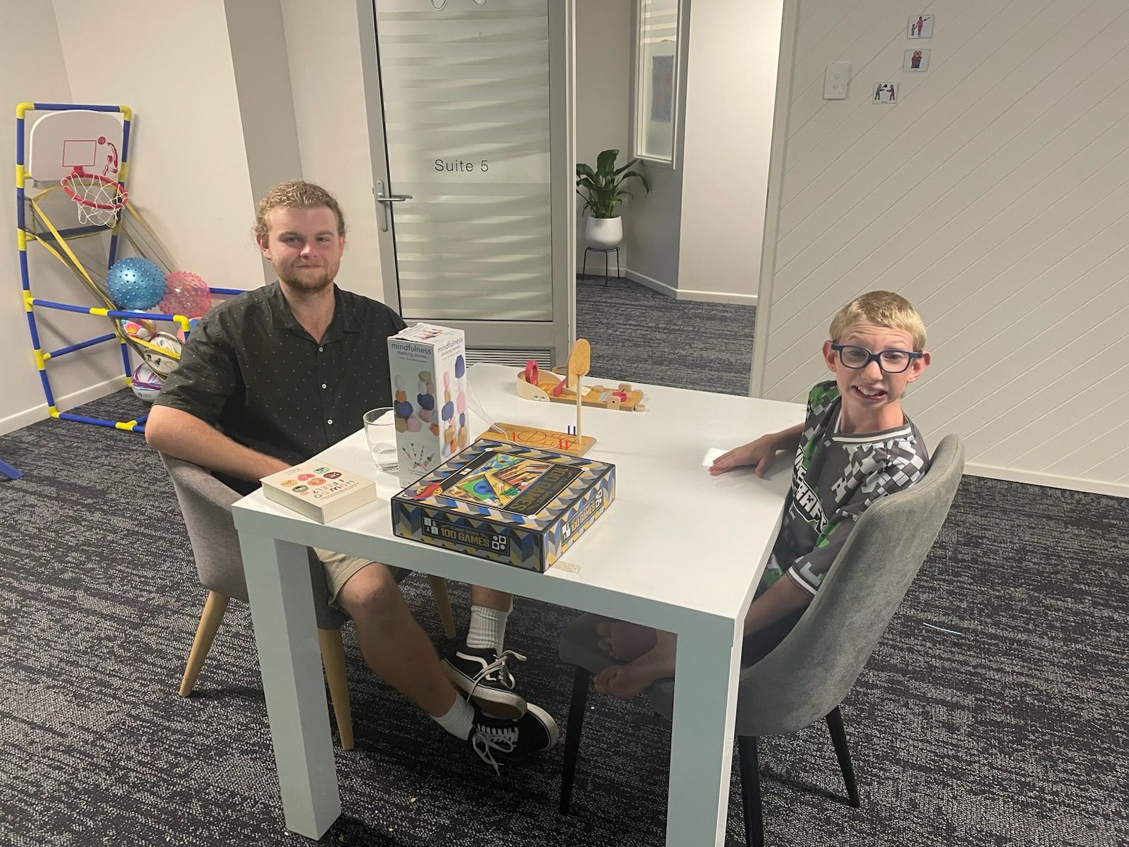Two People Sit At A White Table In An Office Setting Playing A Board Game — Advanced Therapy Mackay In Mackay, QLD 