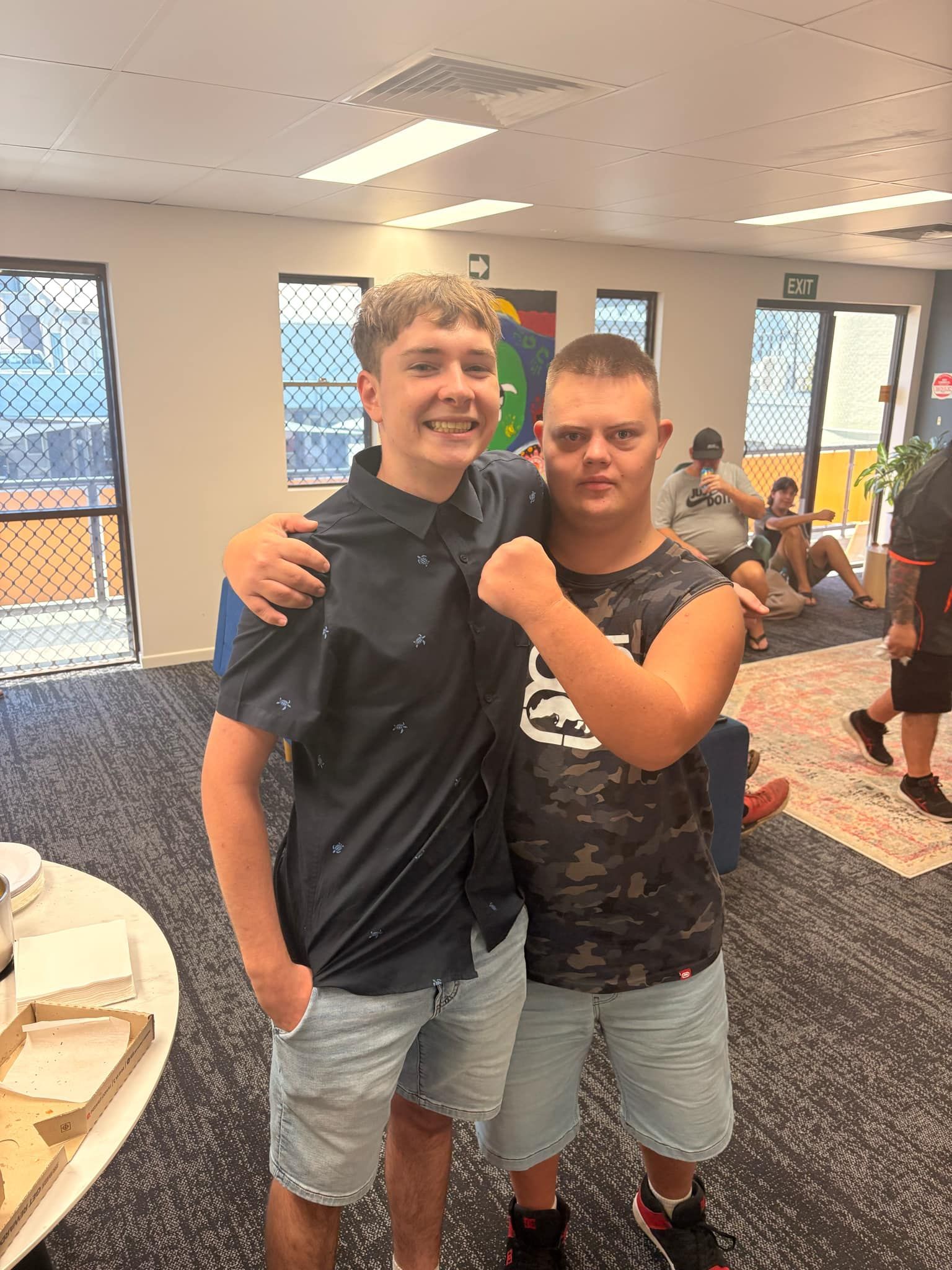 Two people smile and pose for a photo in a brightly lit indoor space with carpeted flooring and large windows — Advanced Therapy Mackay In Mackay, QLD 