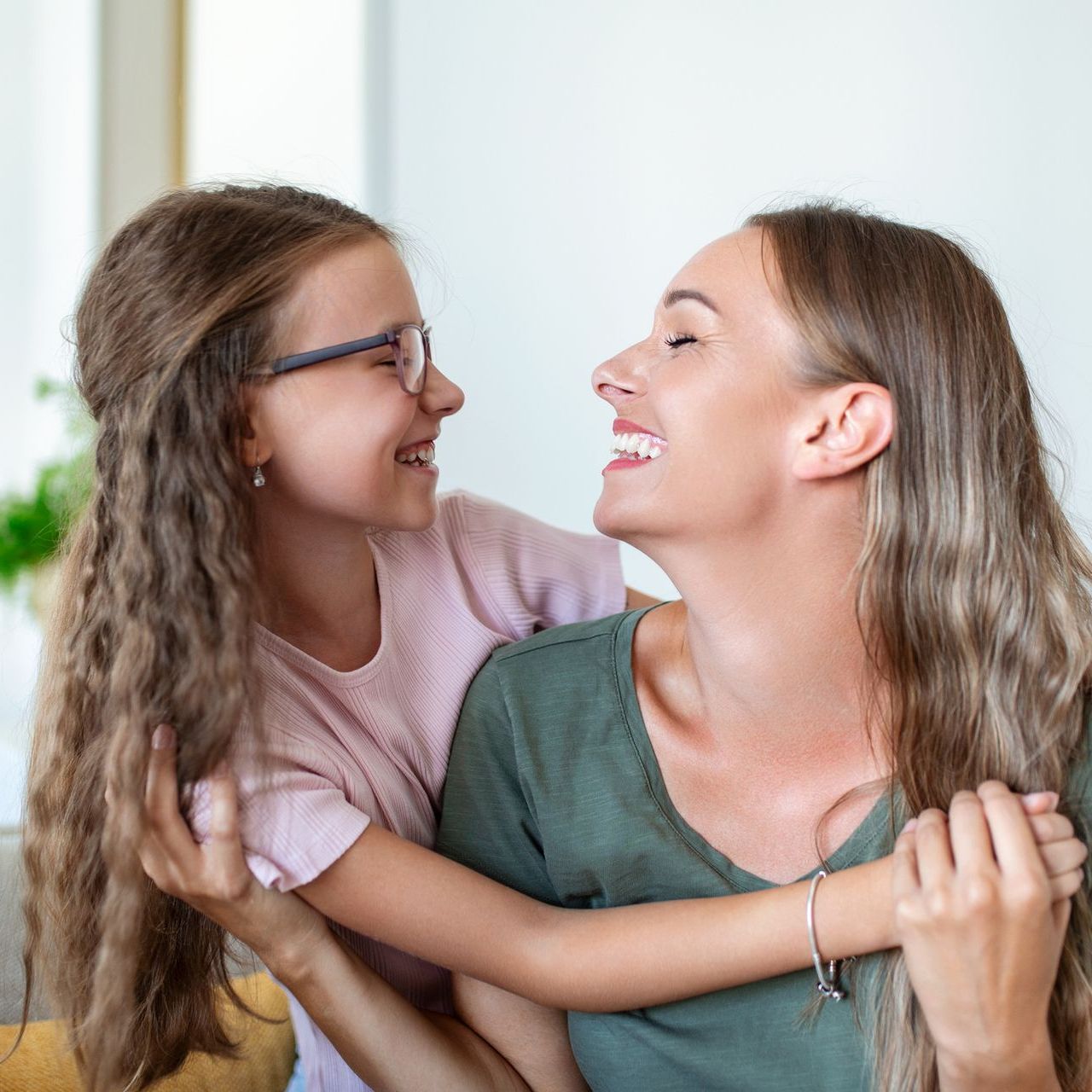 A woman and a little girl are hugging each other and smiling.