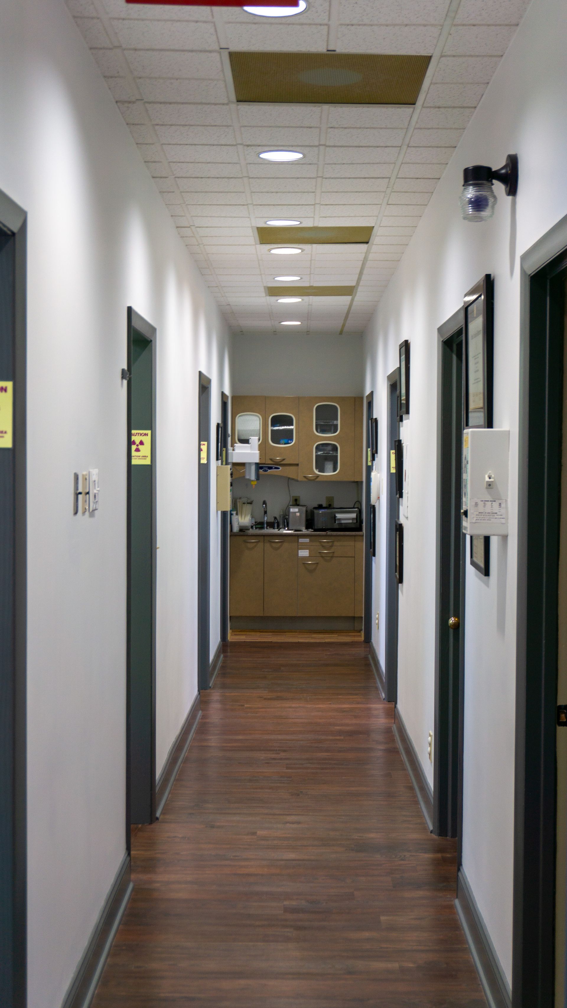 A long hallway with wooden floors and a kitchen in the background.