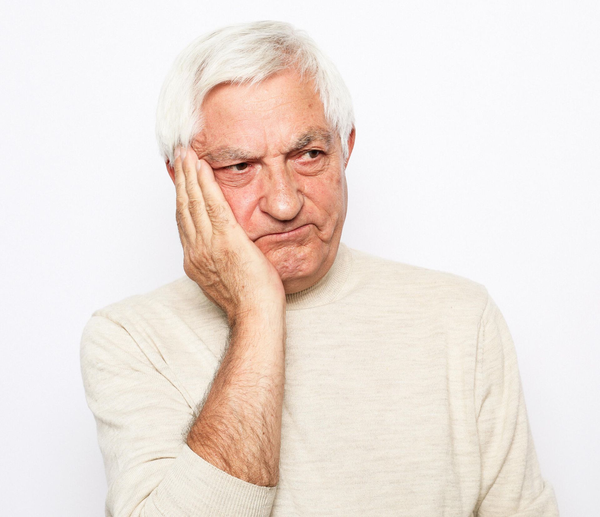 An elderly man is holding his hand to his face because he has a toothache.