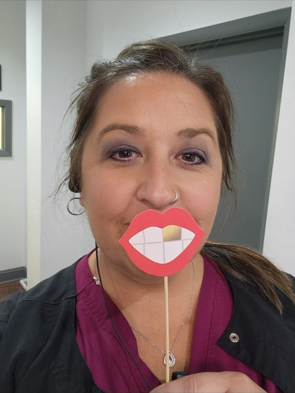 A woman is wearing a fake mouth on a stick.