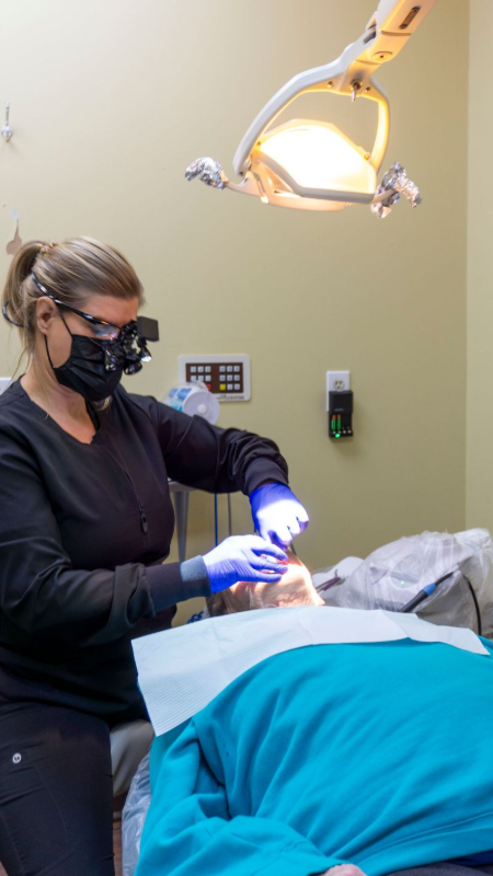 A woman is working on a patient in an operating room.