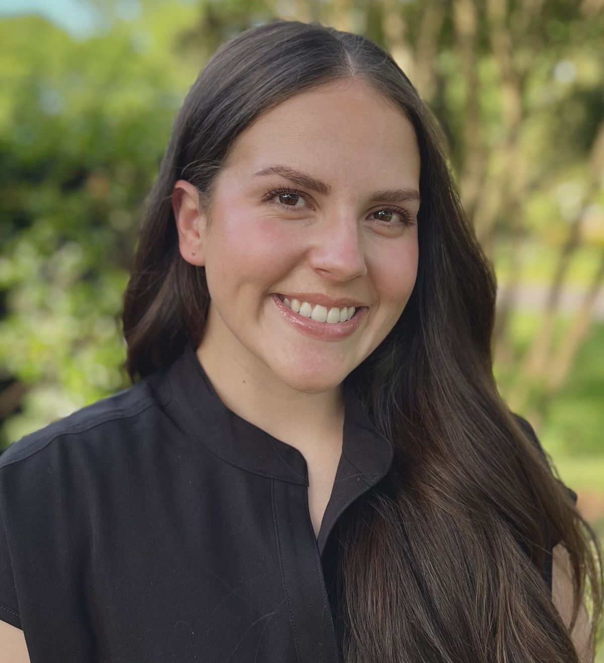 A woman in a black shirt is smiling for the camera.
