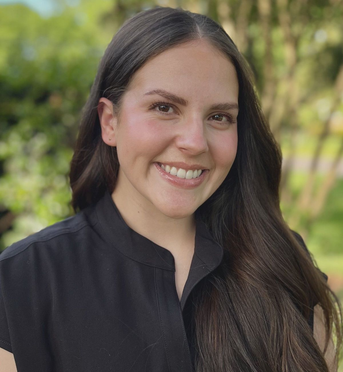 A woman in a black shirt is smiling for the camera.