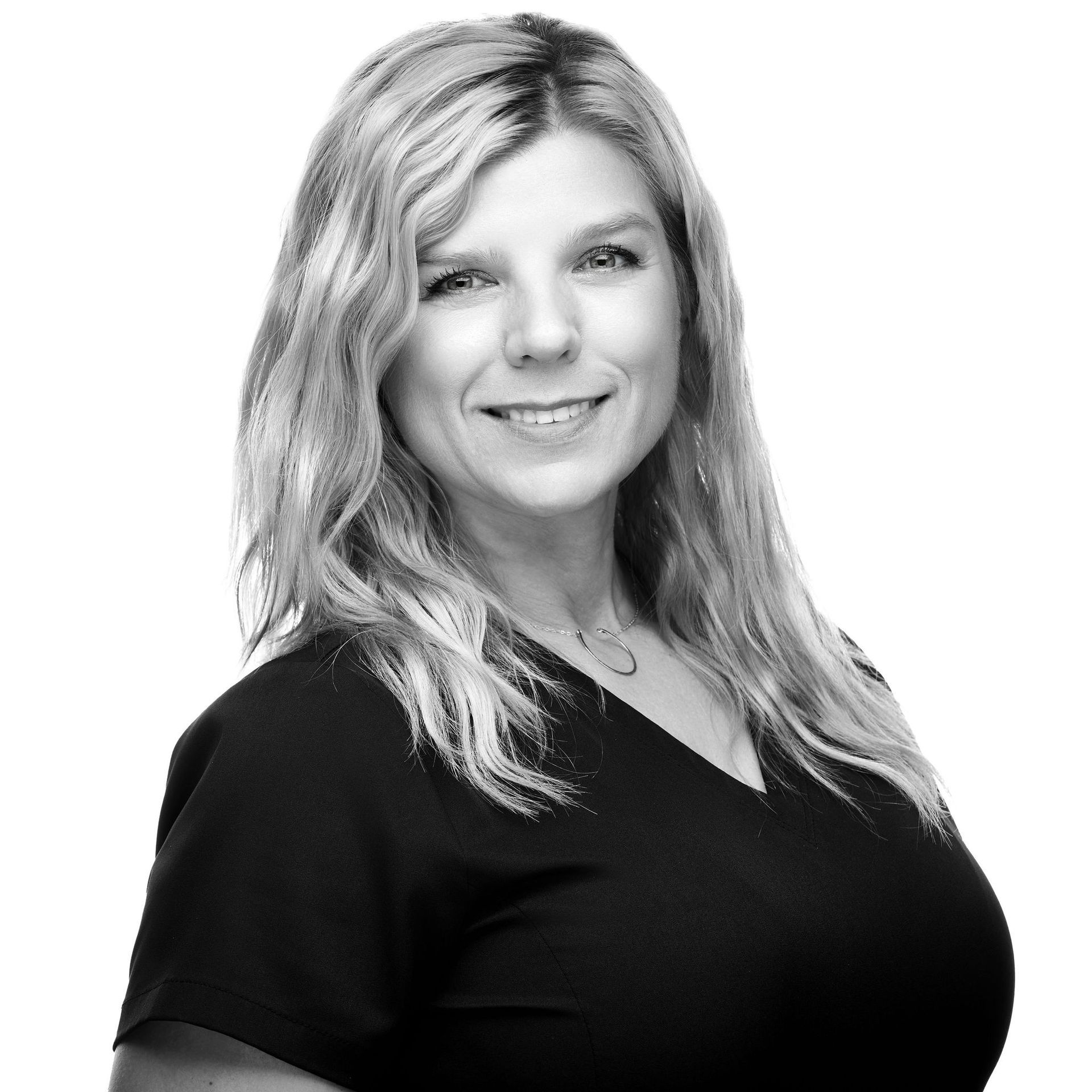 A woman in a black shirt is smiling in a black and white photo.