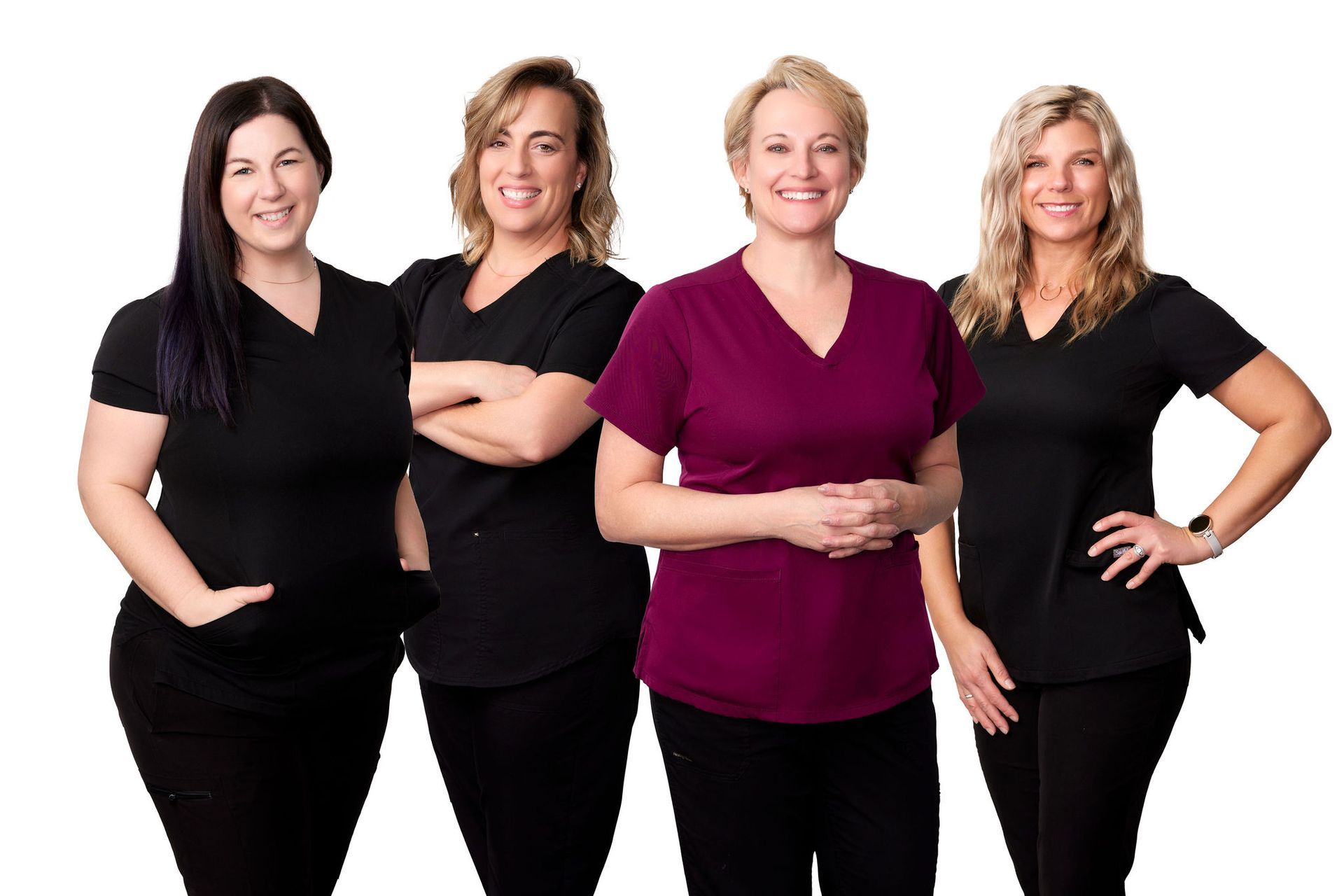 Four women in scrubs are standing next to each other on a white background.