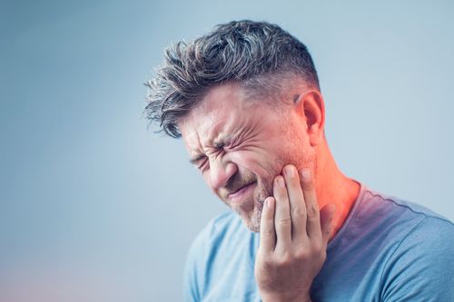 A man is holding his face in pain because of a toothache.