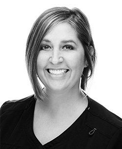A black and white photo of a smiling woman wearing a black shirt.