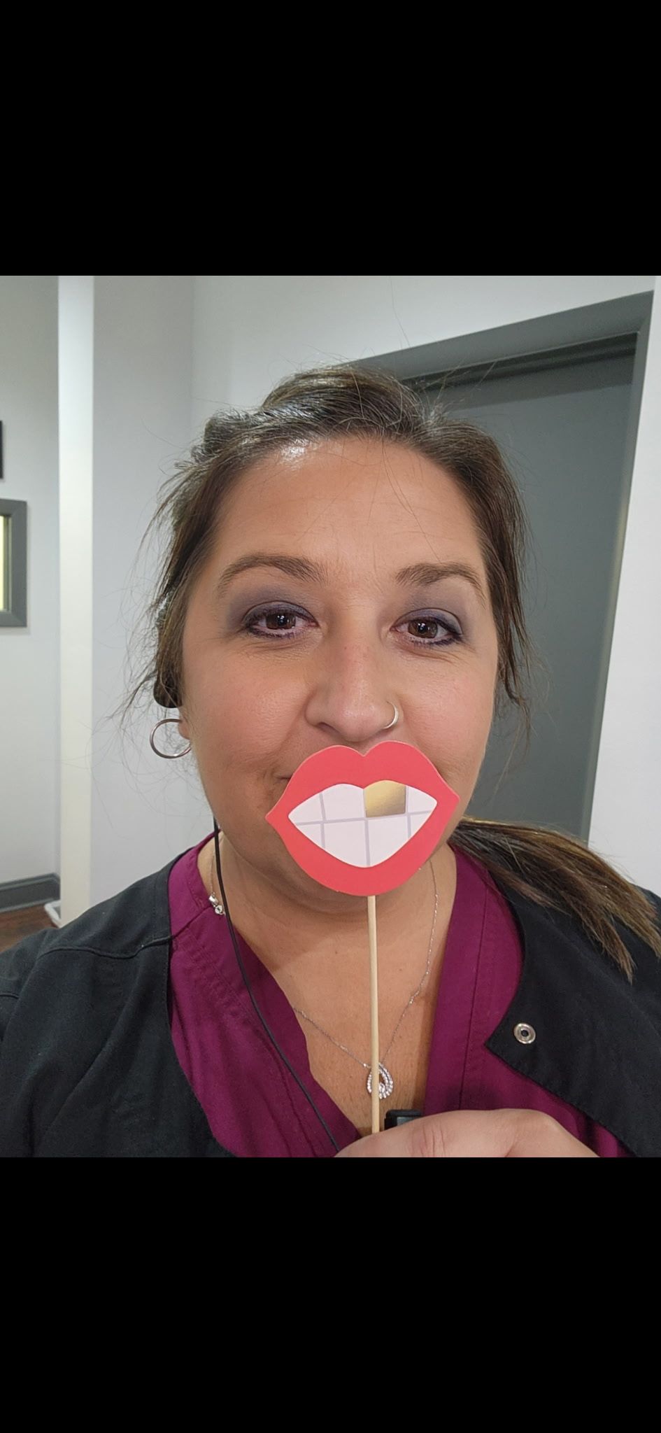 A woman is wearing a fake mouth on a stick.