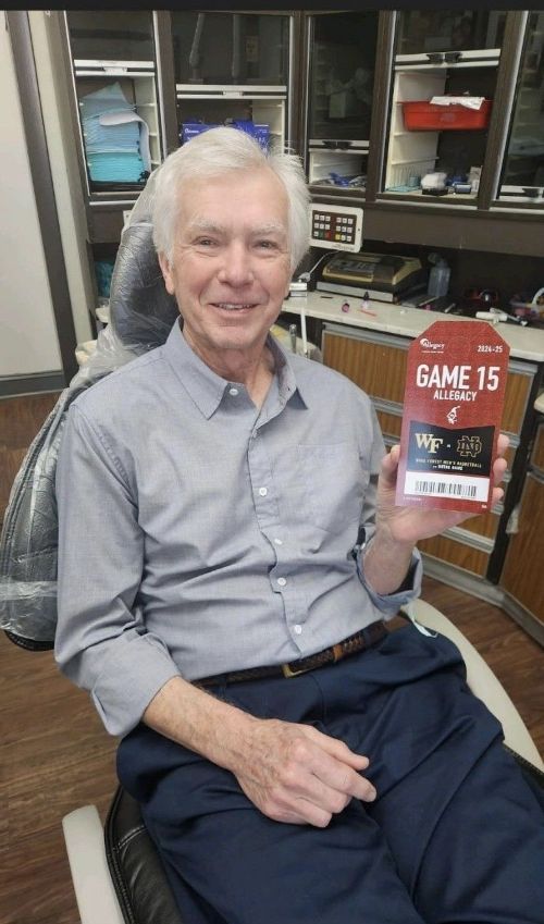 Un hombre está sentado en una silla dental sosteniendo una caja de juguetes.