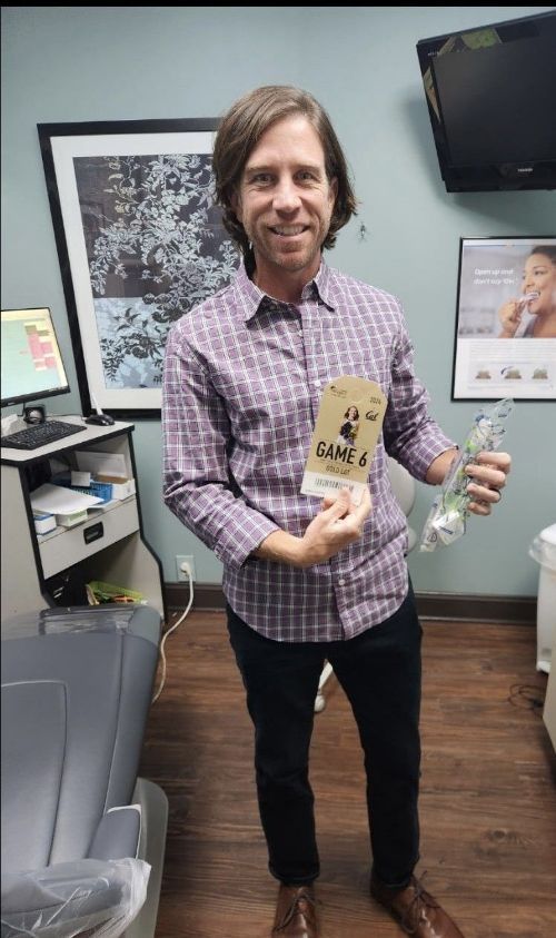 Un hombre está de pie en una habitación sosteniendo un trozo de papel.