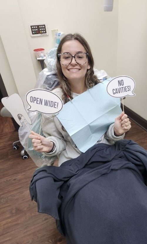 Woman in dentist chair holding signs: 