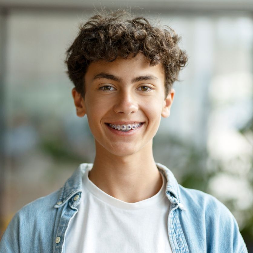 A young man with braces on his teeth is smiling for the camera.