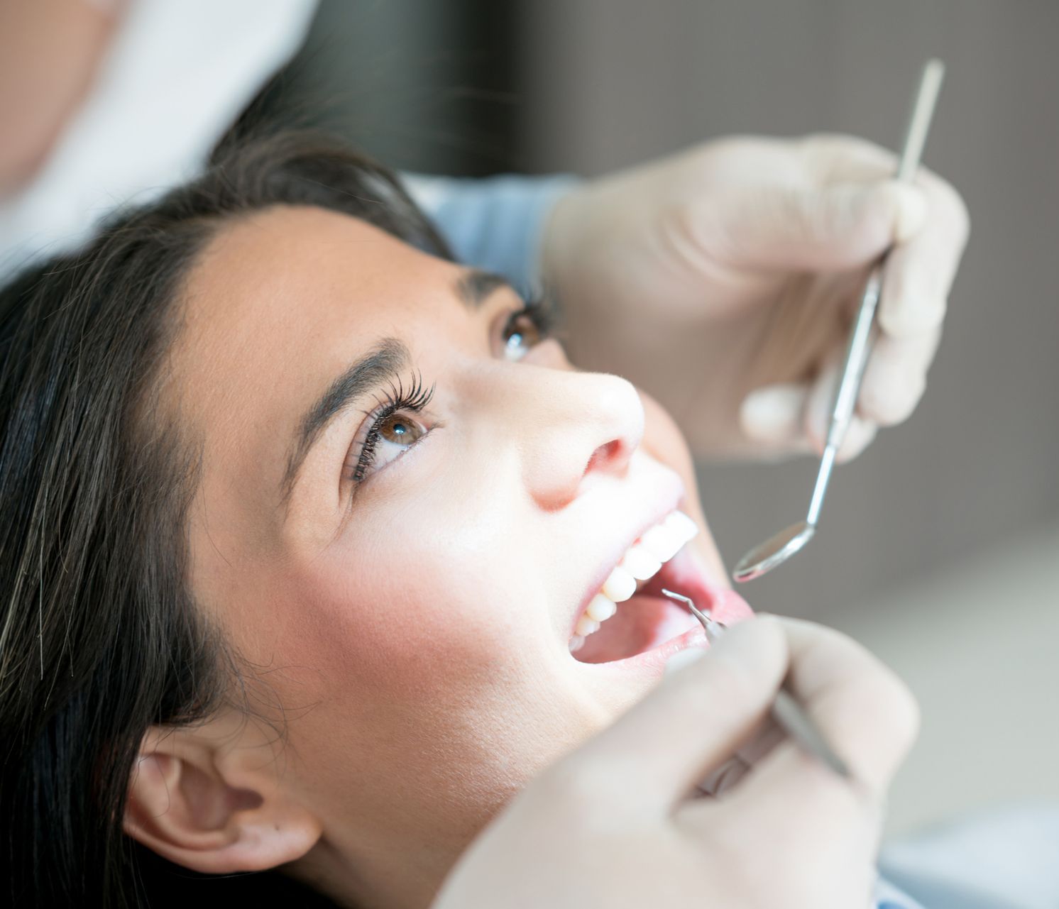 A woman is getting her teeth examined by a dentist.