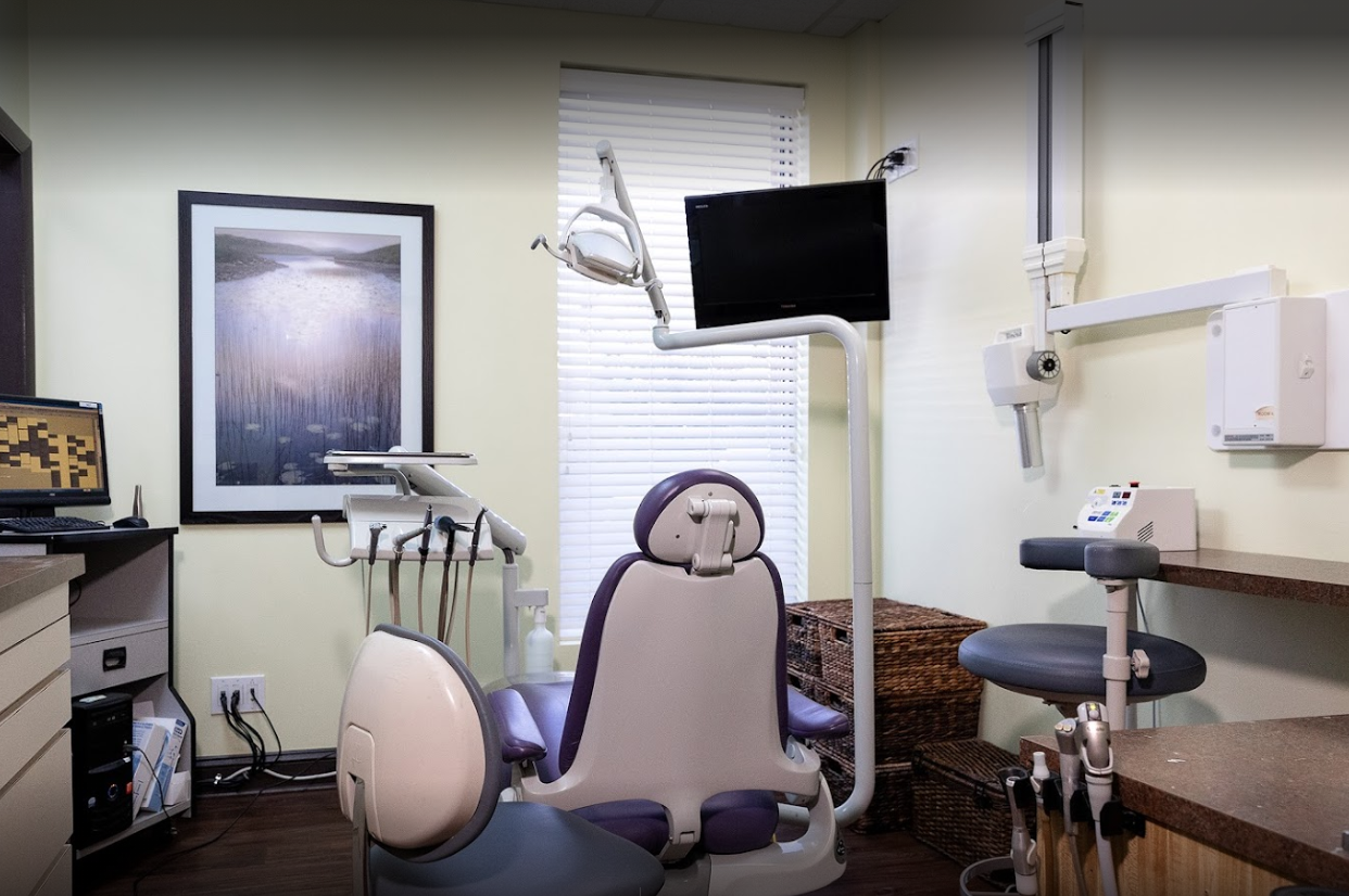 Un consultorio dental con una silla morada y un televisor.