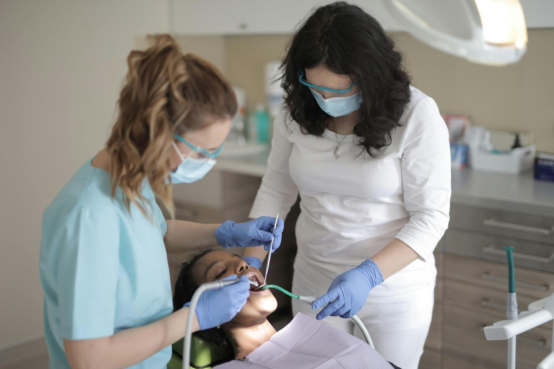 A dentist and a nurse are examining a patient 's teeth in a dental office.