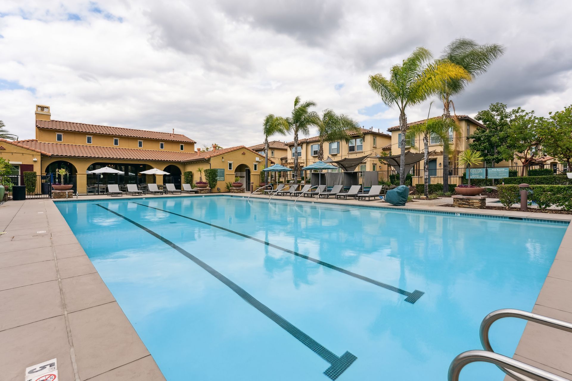 A large swimming pool in front of a building with palm trees.