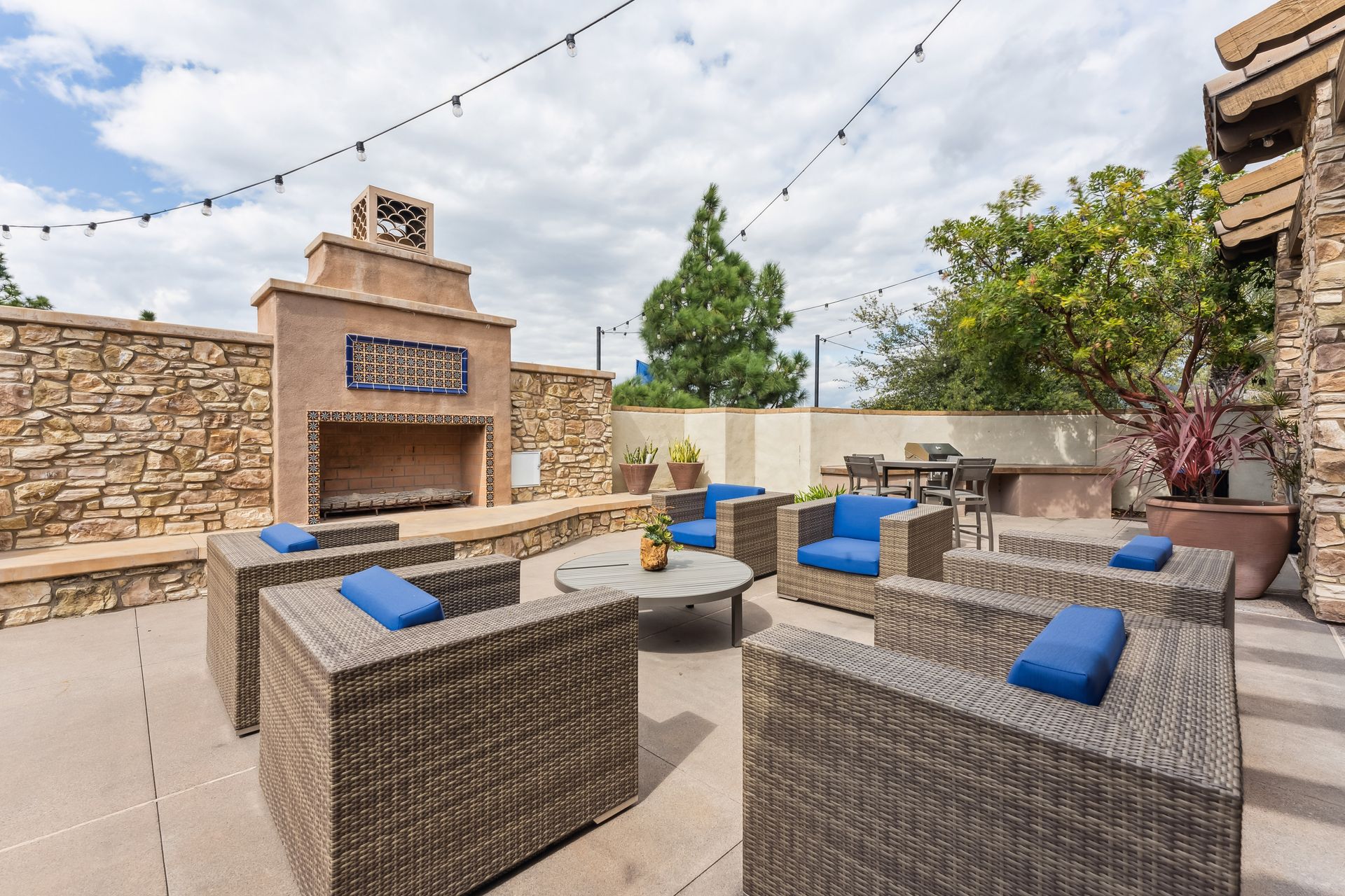 A patio with wicker furniture and a fireplace.
