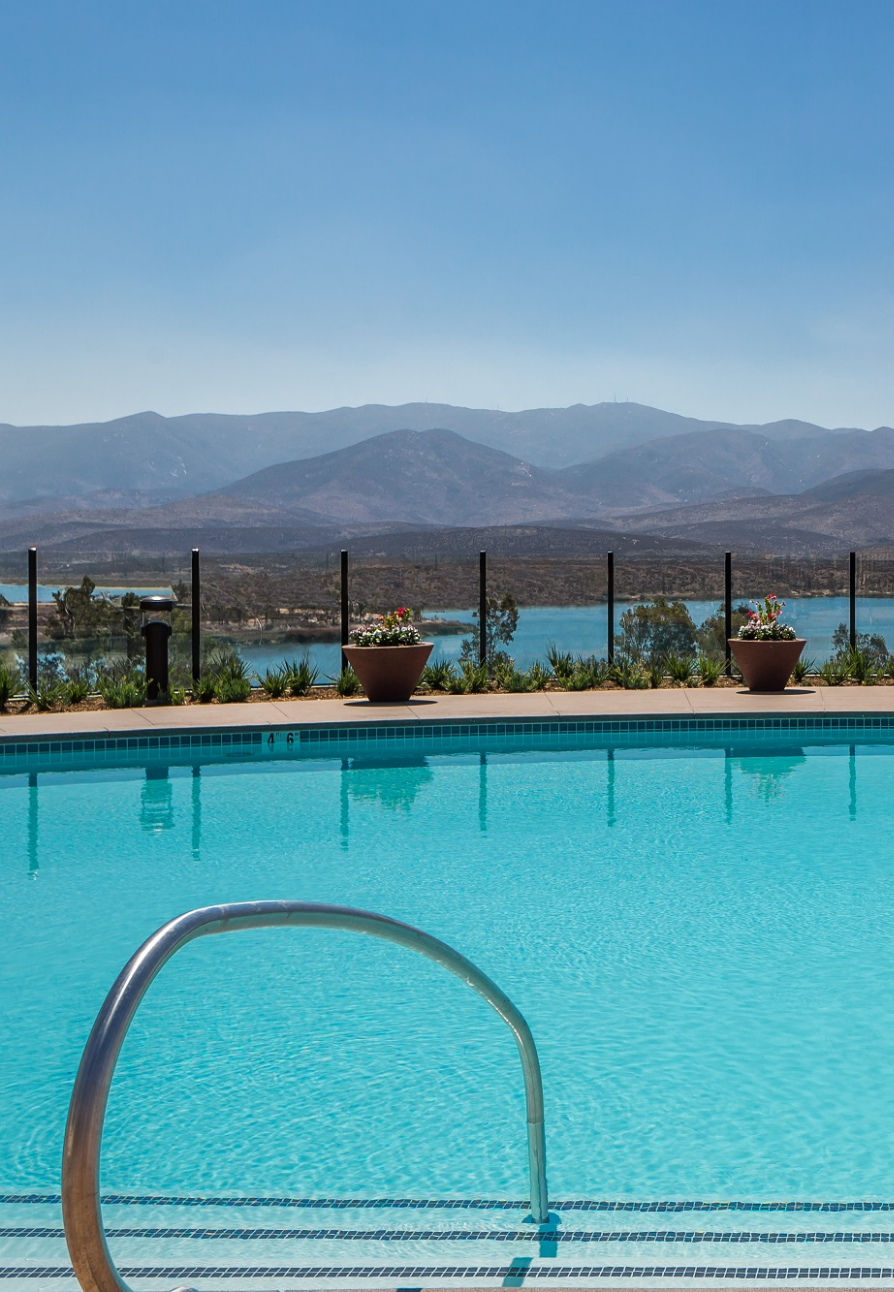 A large swimming pool with a view of a lake and mountains in the background.