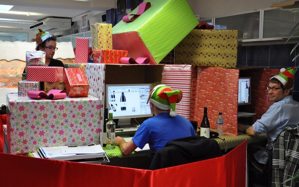 A man wearing a santa hat is sitting at a desk in front of a computer.