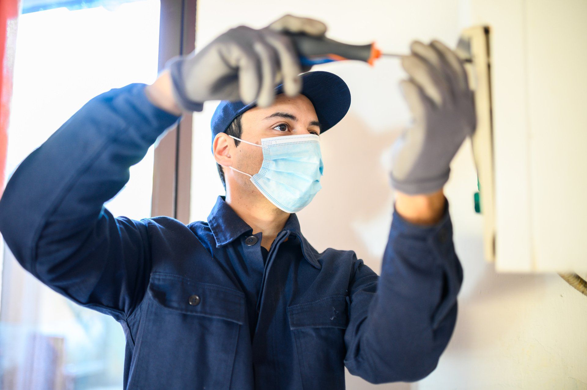 A man wearing a mask and gloves is working on a wall.