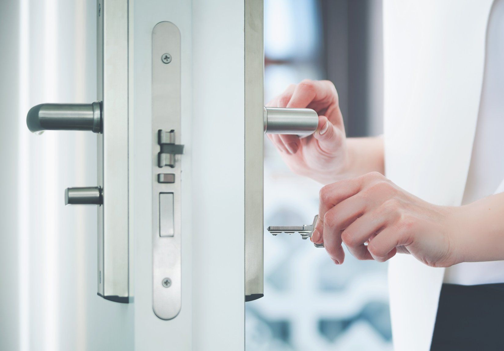 A woman is opening a door with a key.