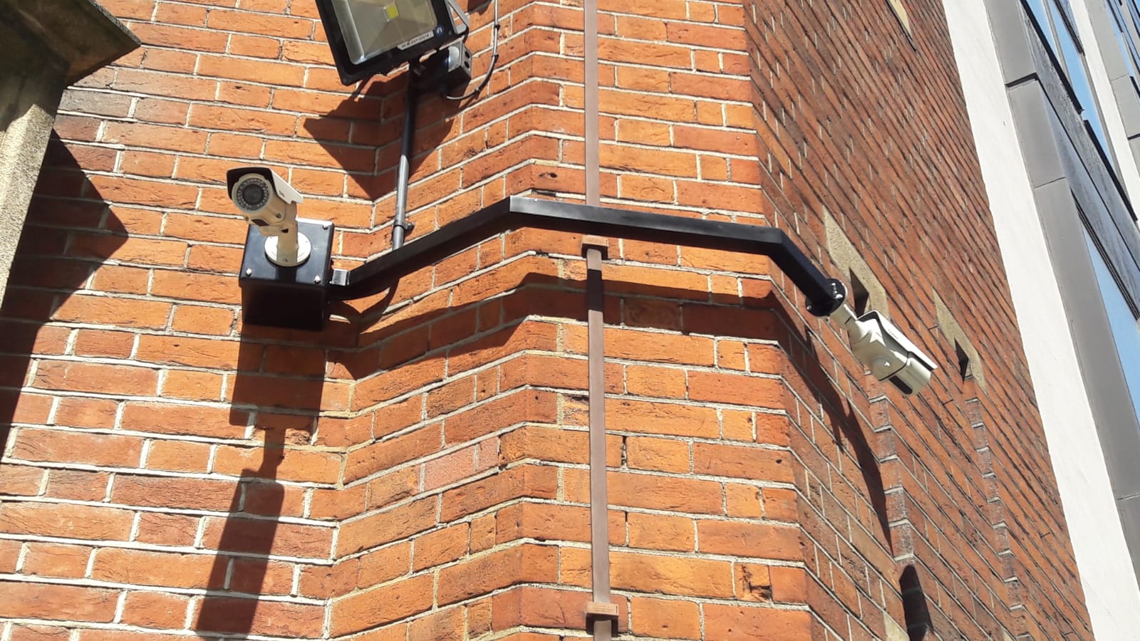 A security camera is mounted on the side of a brick building