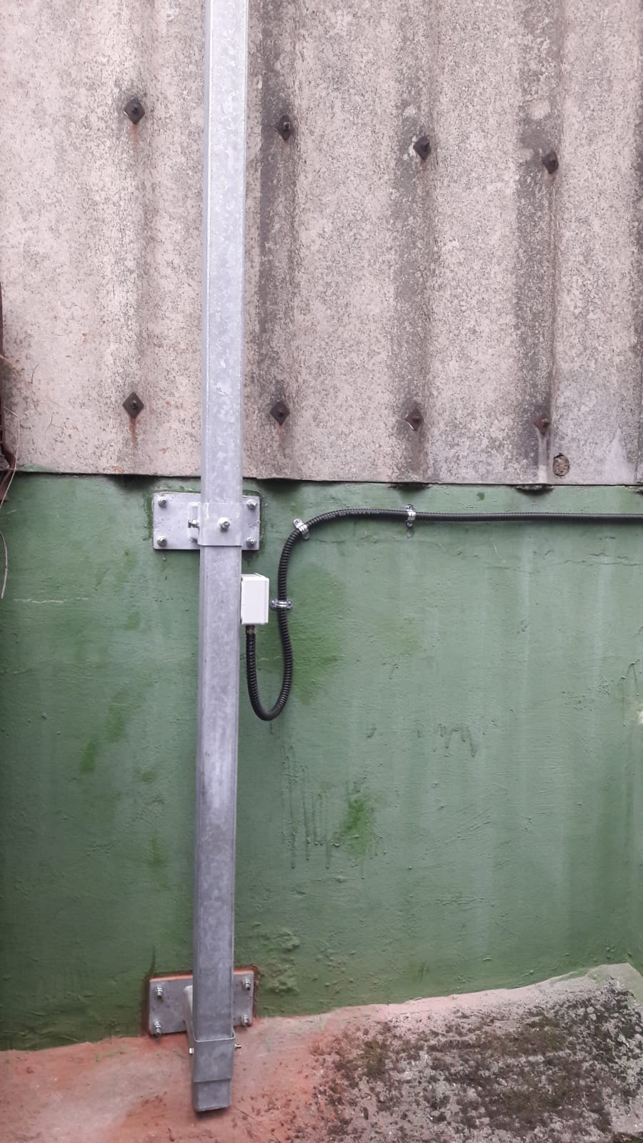 A metal pole is attached to a green wall.