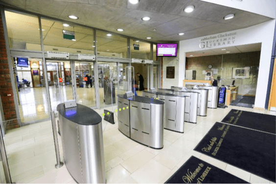 A row of stainless steel turnstiles in a lobby