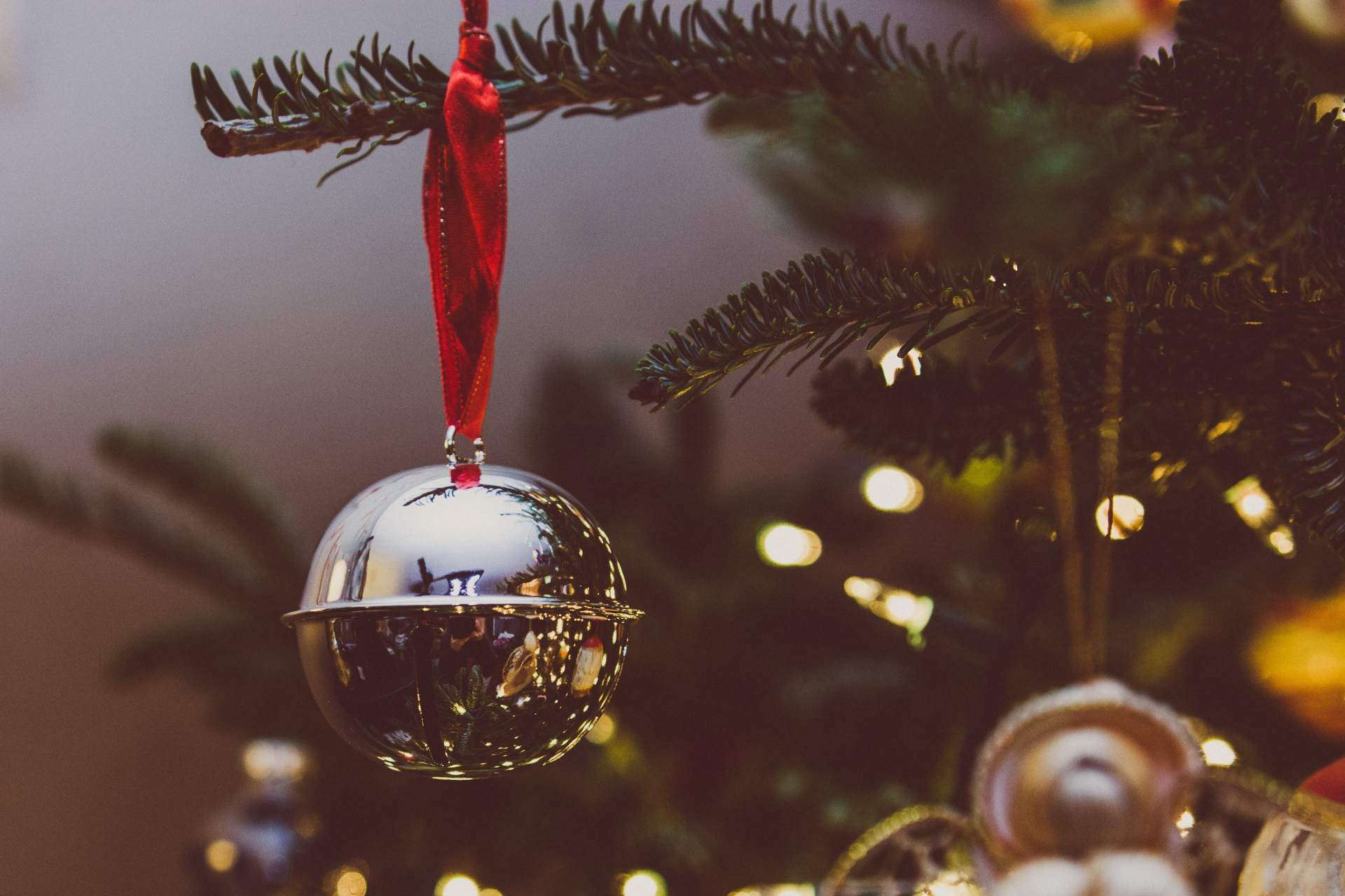 A close up of a christmas tree with a bell hanging from it.