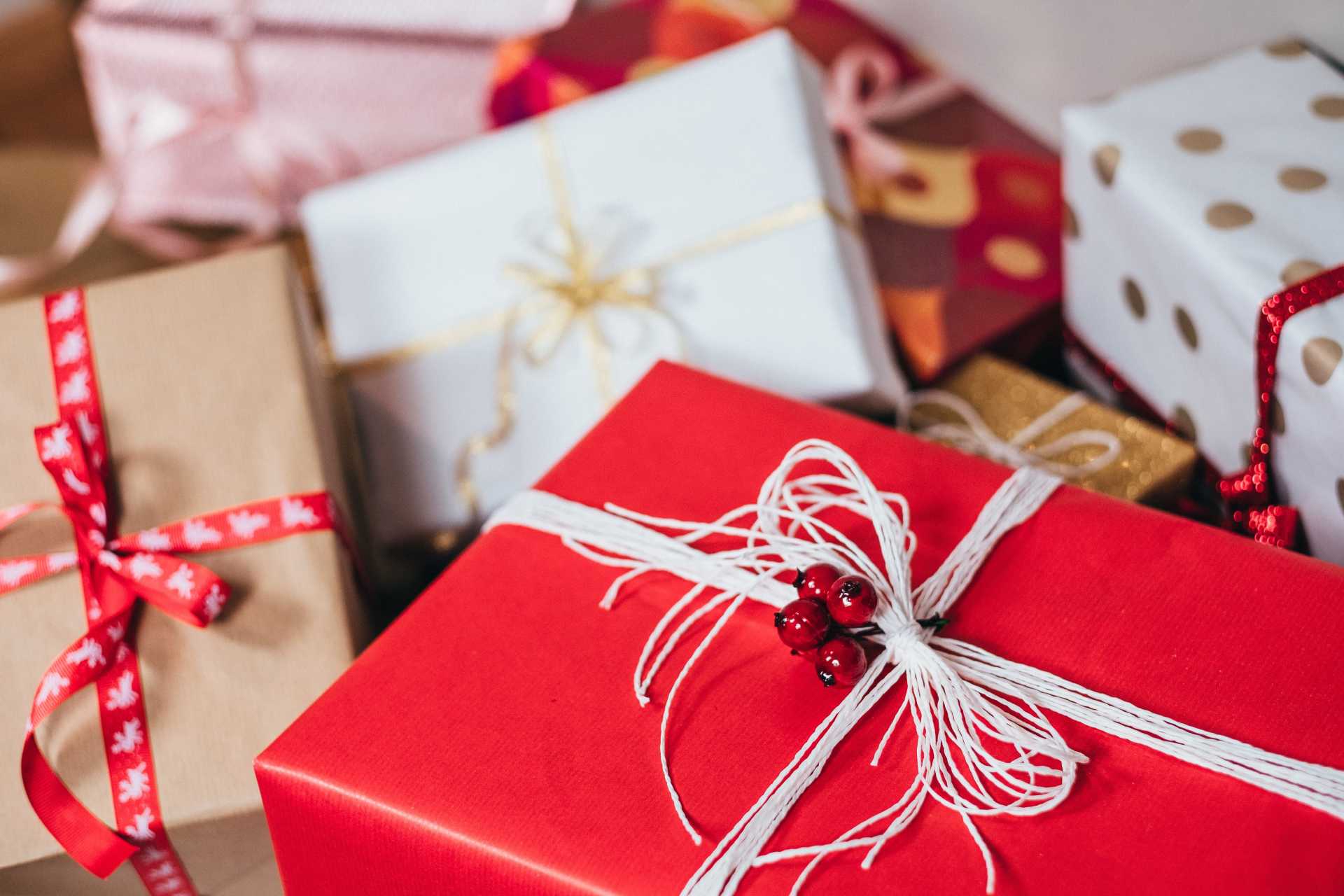 A pile of christmas presents wrapped in red paper and tied with ribbons.