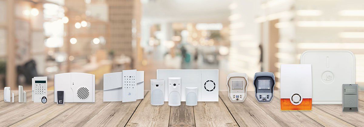 A variety of security systems are lined up on a wooden table.