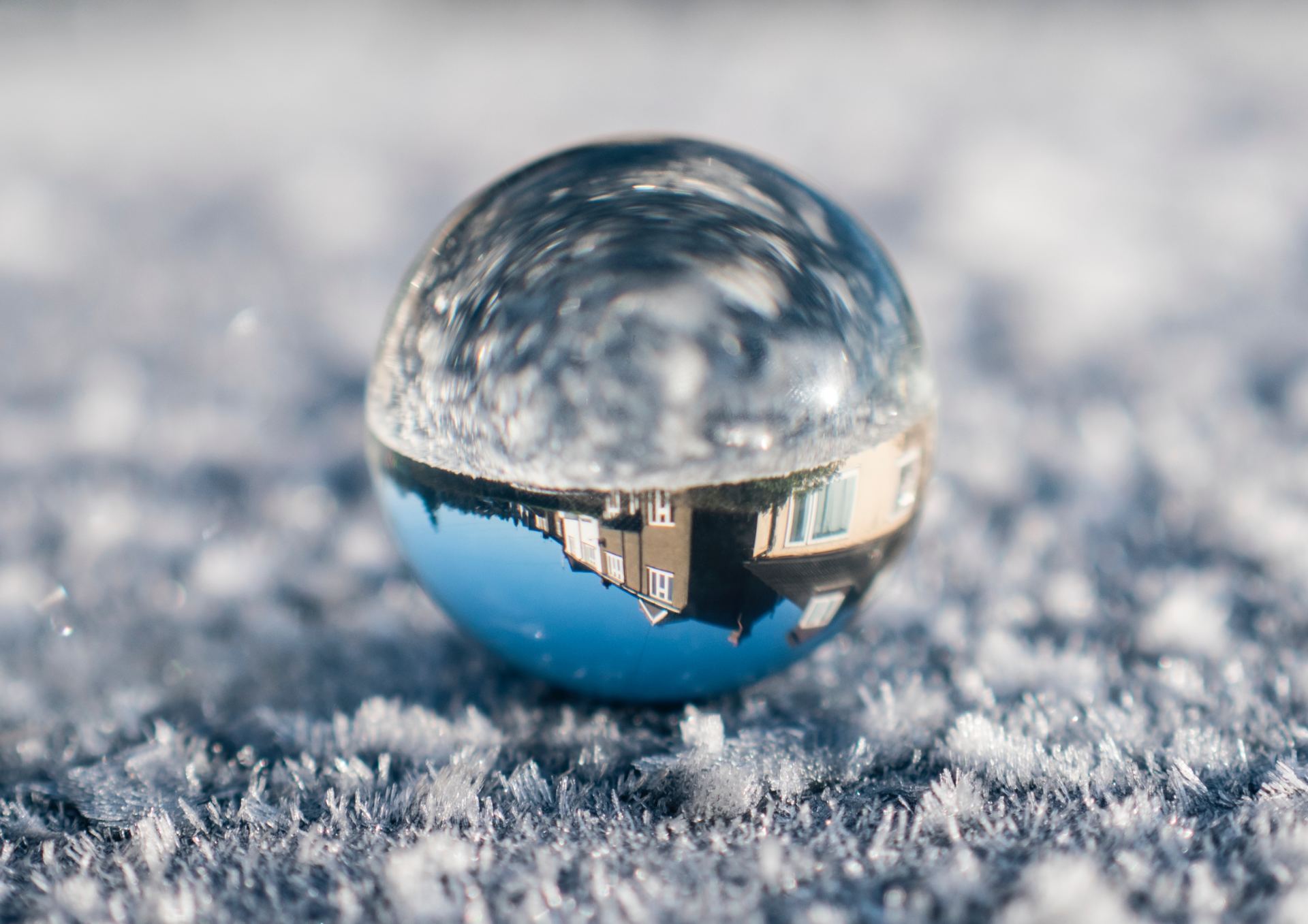 A glass ball is sitting on top of a snowy surface.