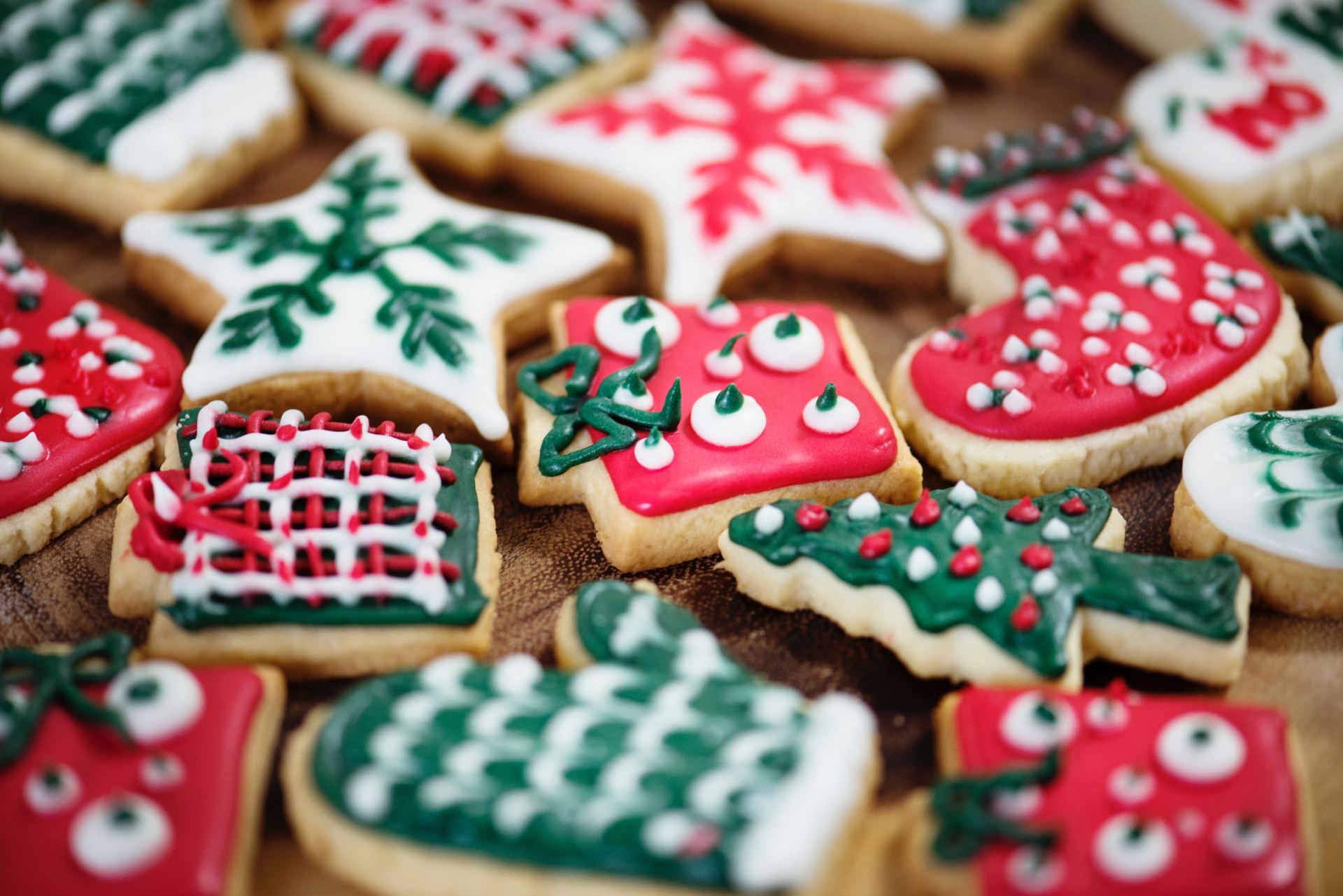 A bunch of decorated christmas cookies are sitting on a wooden table.