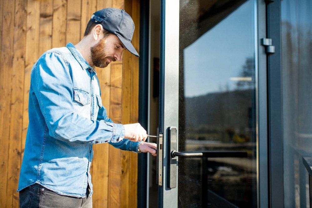 Workman Repairing Entrance Door Lock Of The Modern House — Coastal Screens & Glass in Port Macquarie, NSW