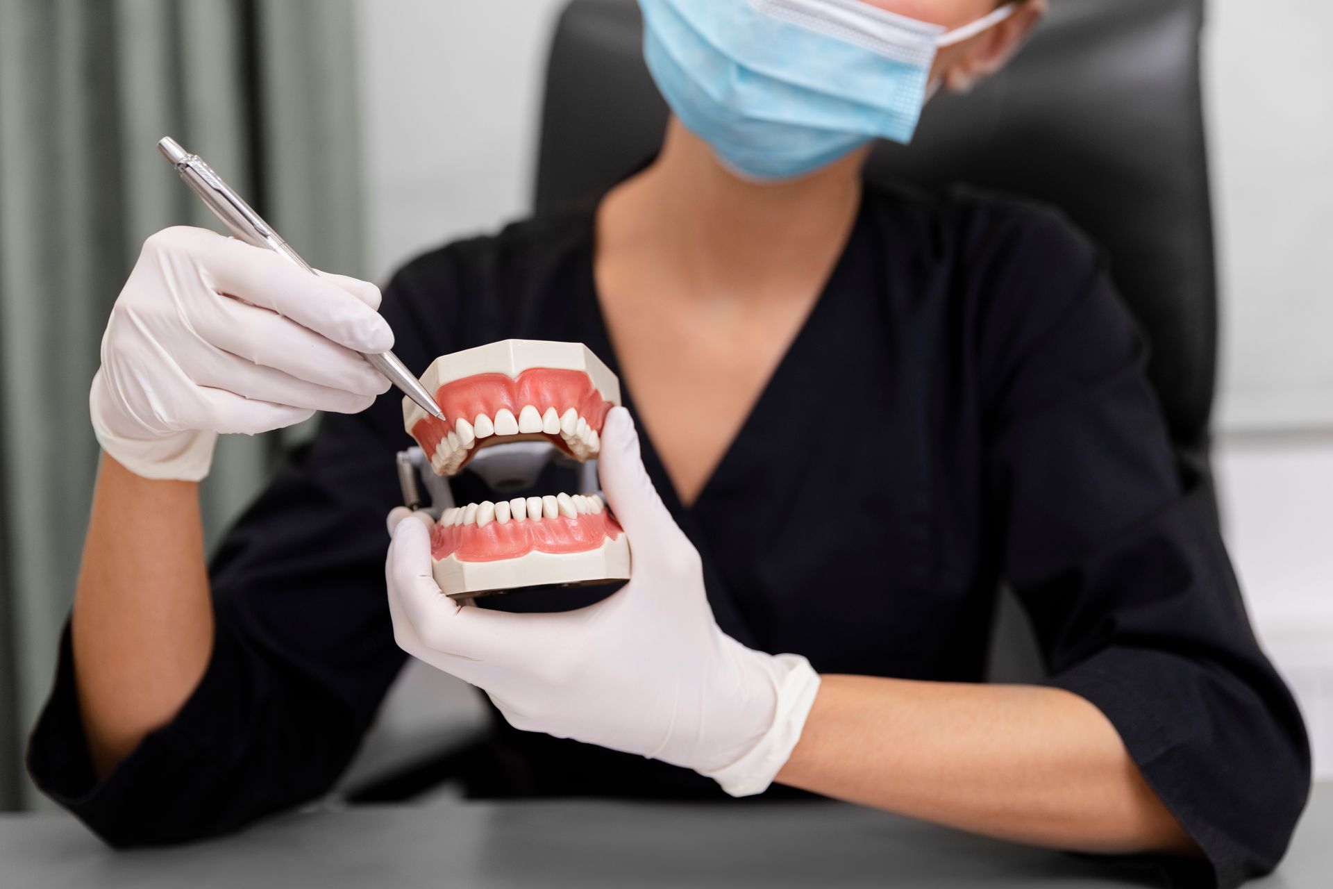 A female dentist is examining a model of a person 's teeth.