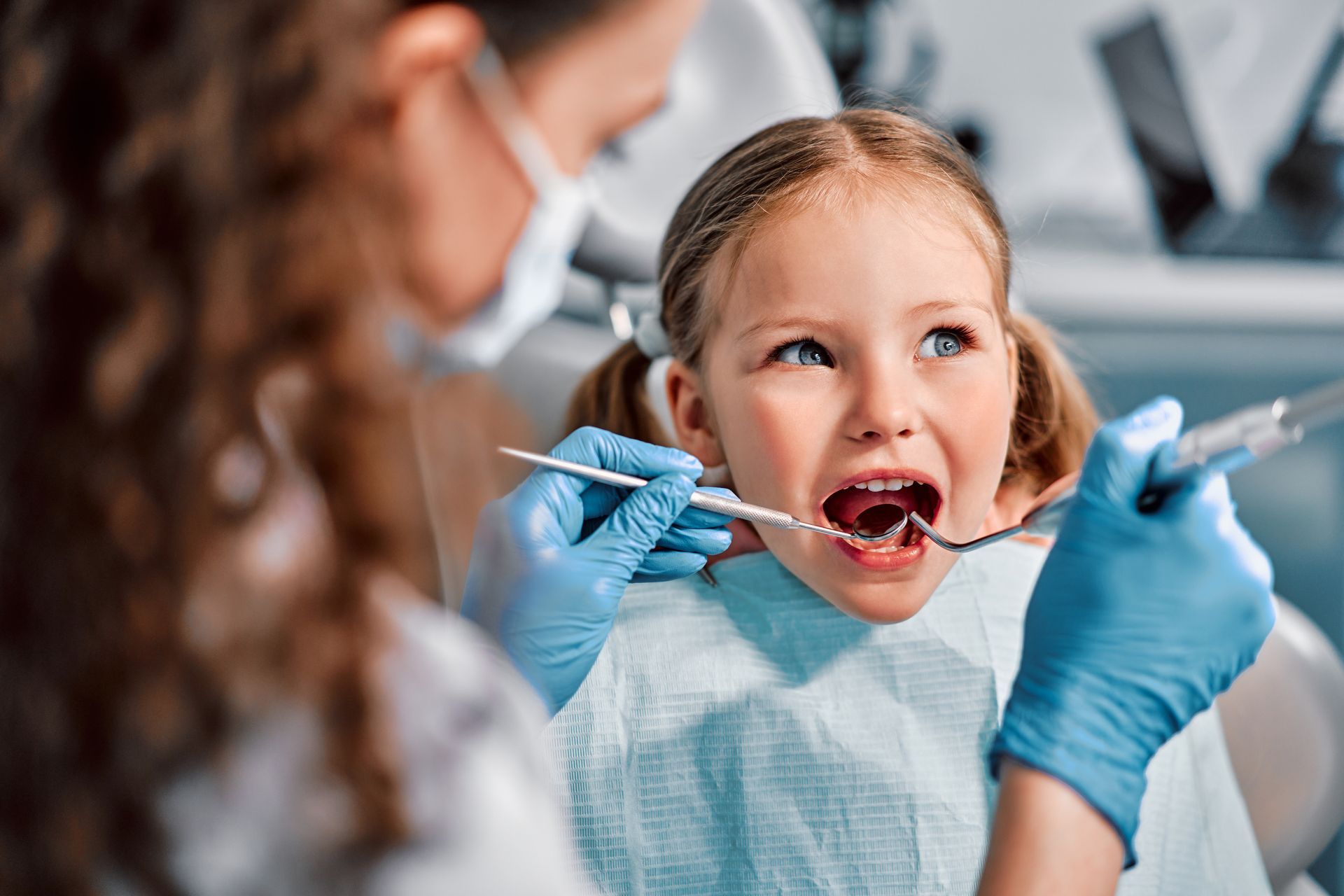 A little girl is getting her teeth examined by a dentist.