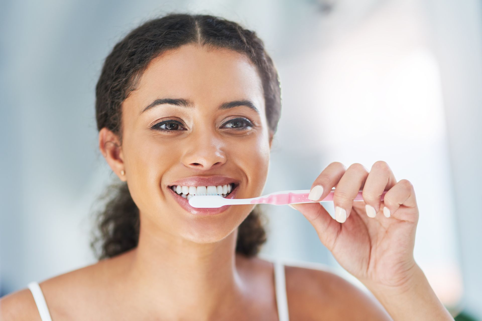 A woman is brushing her teeth in front of a mirror.