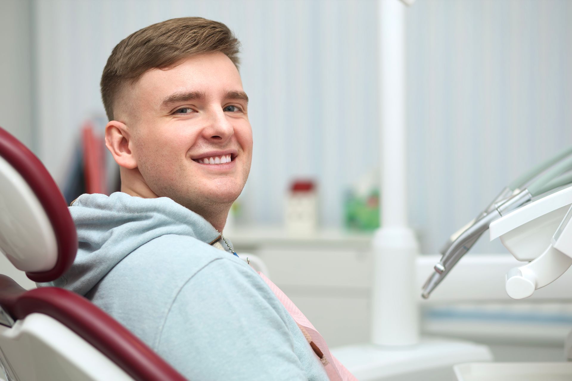 A young man is sitting in a dental chair and smiling.