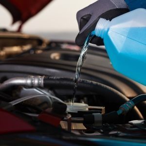 A person pouring water into a car engine