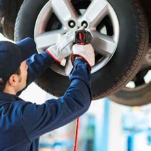 A man is changing a tire on a car in a garage.