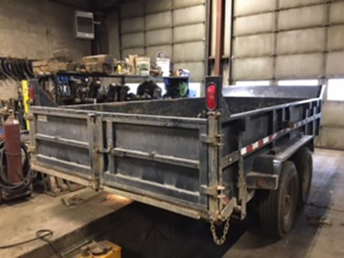 A dump trailer is parked in a garage next to a garage door.