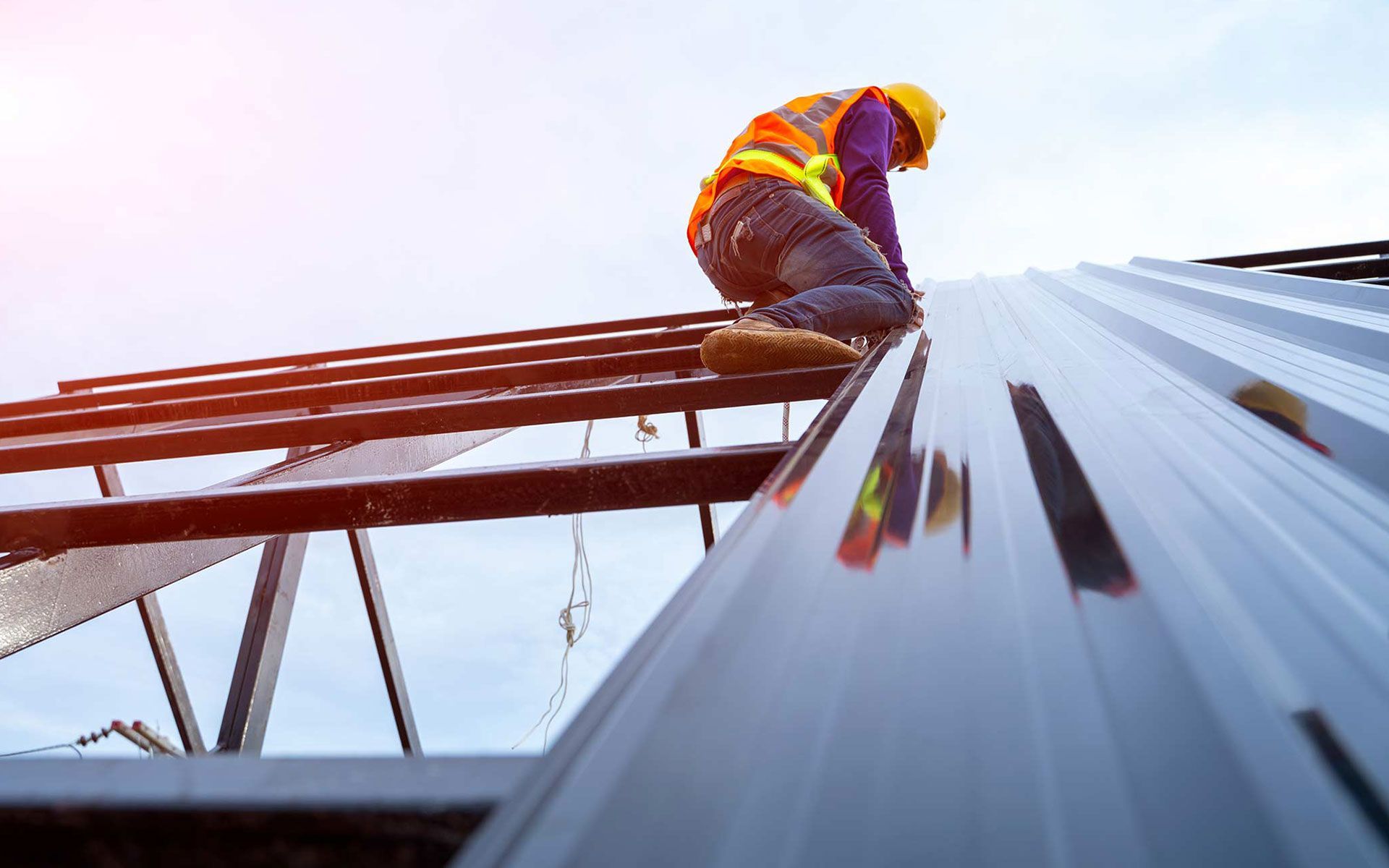A construction worker is working on the roof of a building.