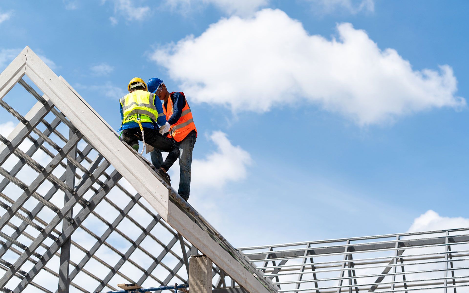 Two construction workers are working on the roof of a building.