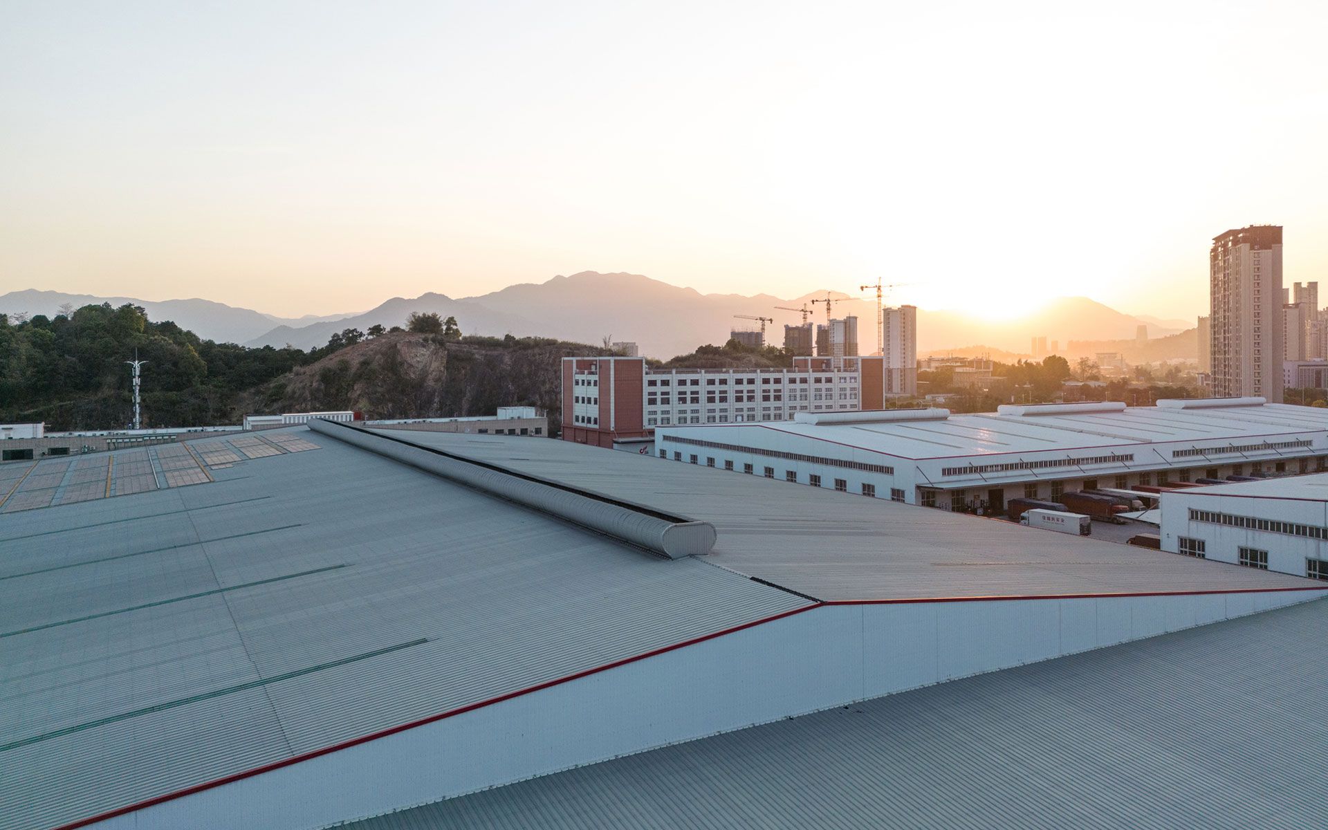 An aerial view of a rooftop of a building with mountains in the background at sunset.