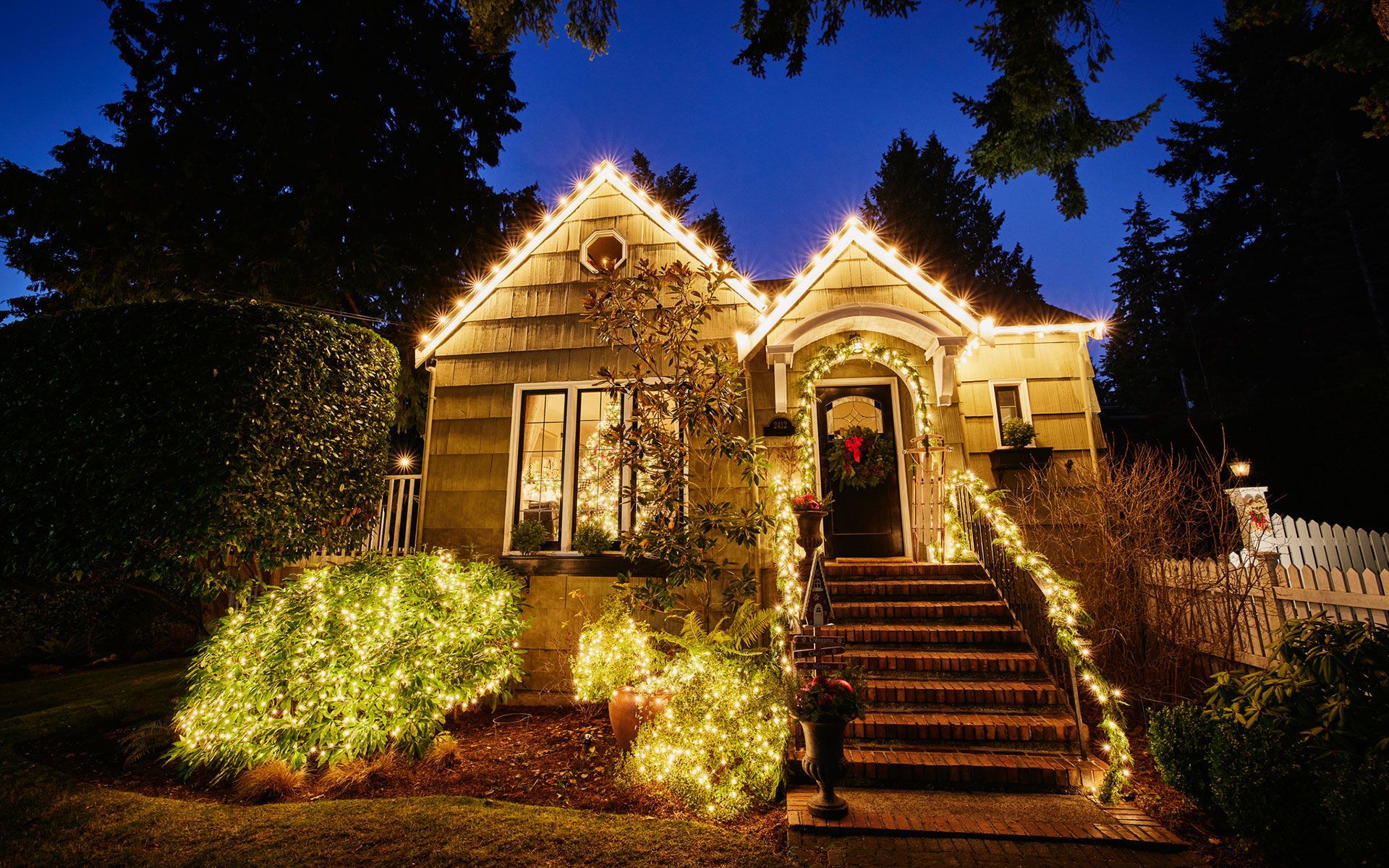 A house decorated with christmas lights is lit up at night.